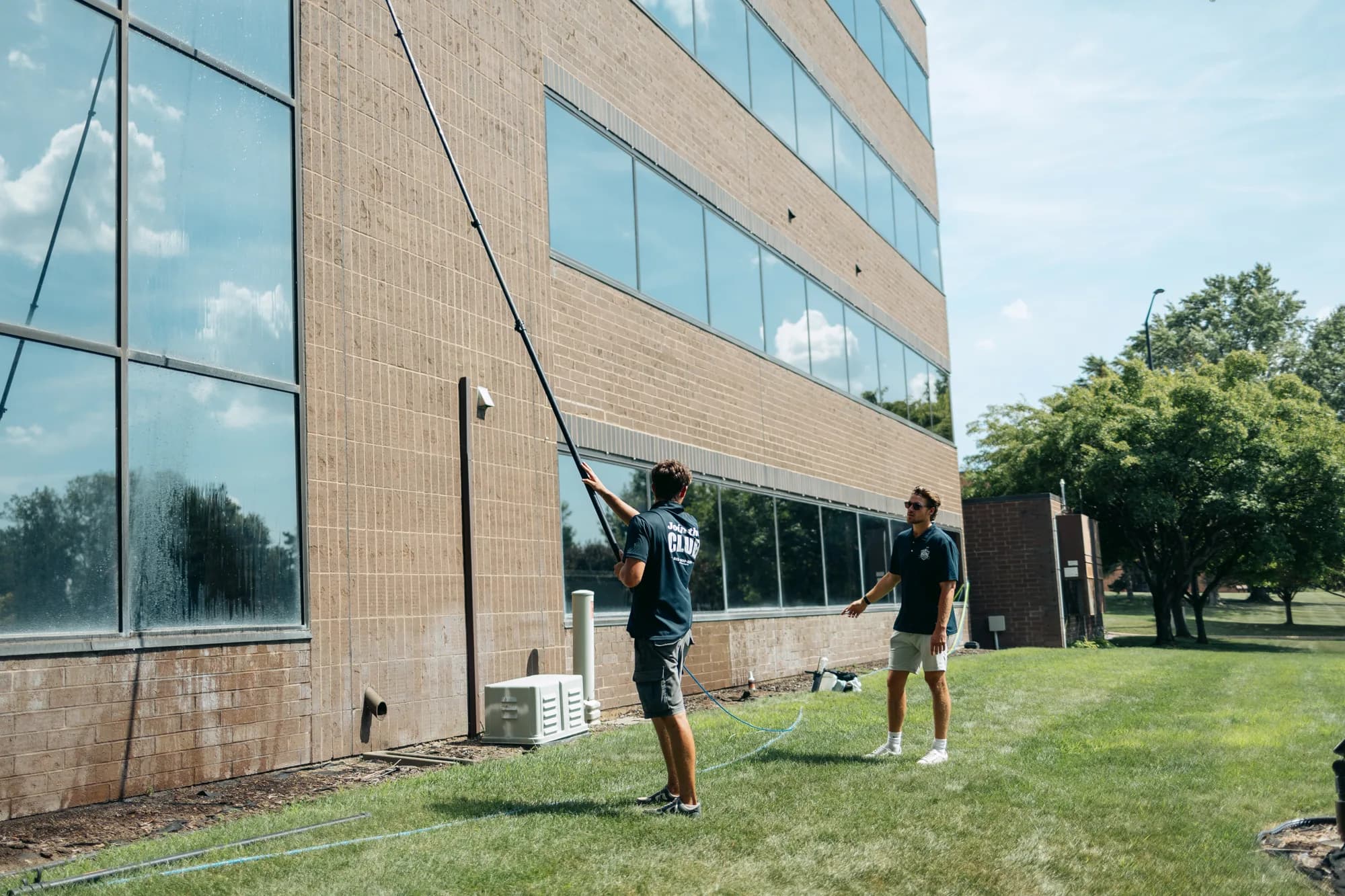 Two-person FCR crew using a water-fed pole to clean a multi-story office building